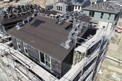 dwellings under construction surrounded by scaffolding with rooftops covered in stacks of tiles for installation