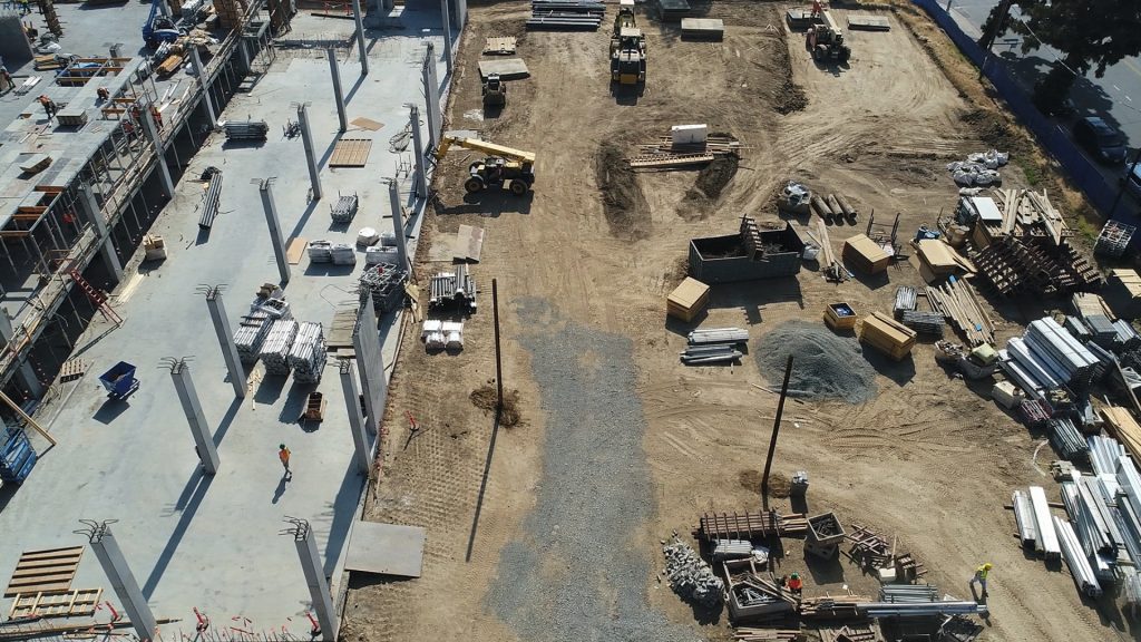 aerial view of a construction site with stockpiles, other materials, workers and equipment scattered throughout the area